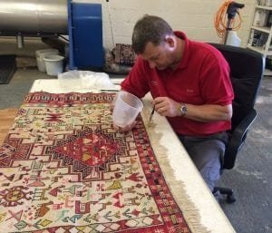 Professional Rug Cleaning in Derby - www.FloorCareSpecialists.co.uk Technician assessing a patterned rug before professional cleaning